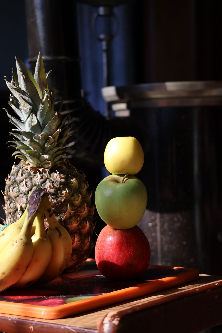Eine lebendige Obstansammlung mit Äpfeln, Bananen und Ananas unter warmem Licht.