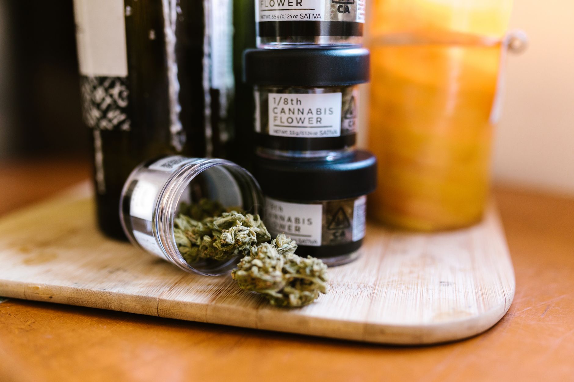 Cannabisblüten in Glasgläsern auf einem Holzbrett drinnen bei weichem Licht.